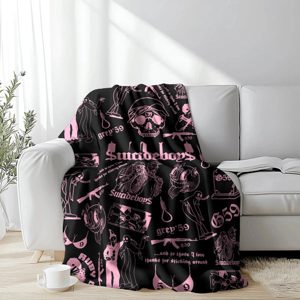 A pink retro punk print blanket draped over a white sofa with bright sunlight streaming in.