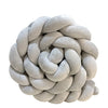 A round, light gray handmade knotted floor mat for bed decor.