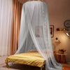 A sheer gray mosquito net canopy draped over a bed, with yellow bedding visible.