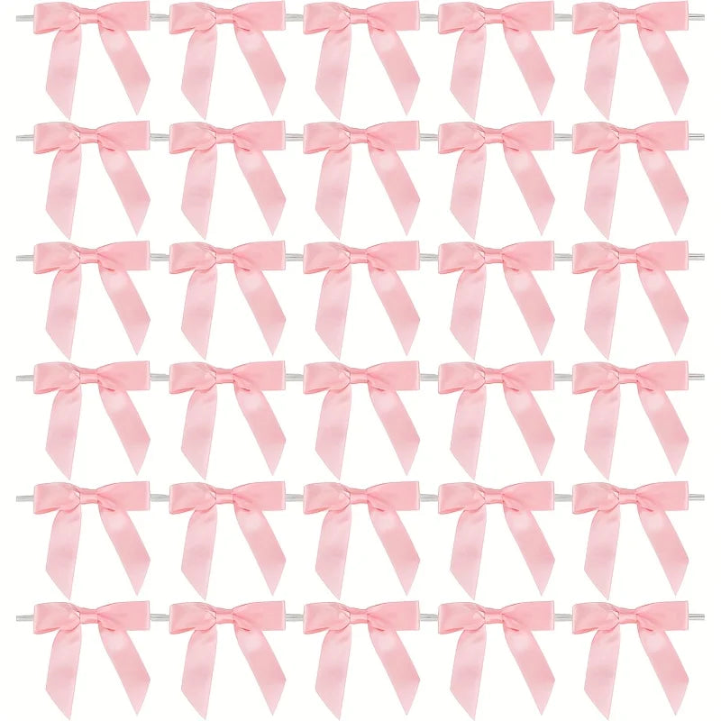 A pack of 50 satin ribbon twist tie bows in various shades of pink.