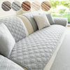 Gray quilted sofa cushion covers with beige accents displayed on a sofa.