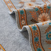 Close-up of a gray chenille sofa cover with colorful geometric embroidery and decorative trim.