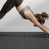 A person performing a yoga pose on a dark fitness floor mat with orange sensor lights.